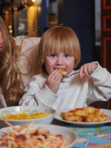 Young child eating chicken tenders at a restaurant table